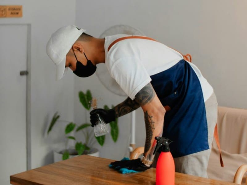 Persona limpiando la mesa de un local